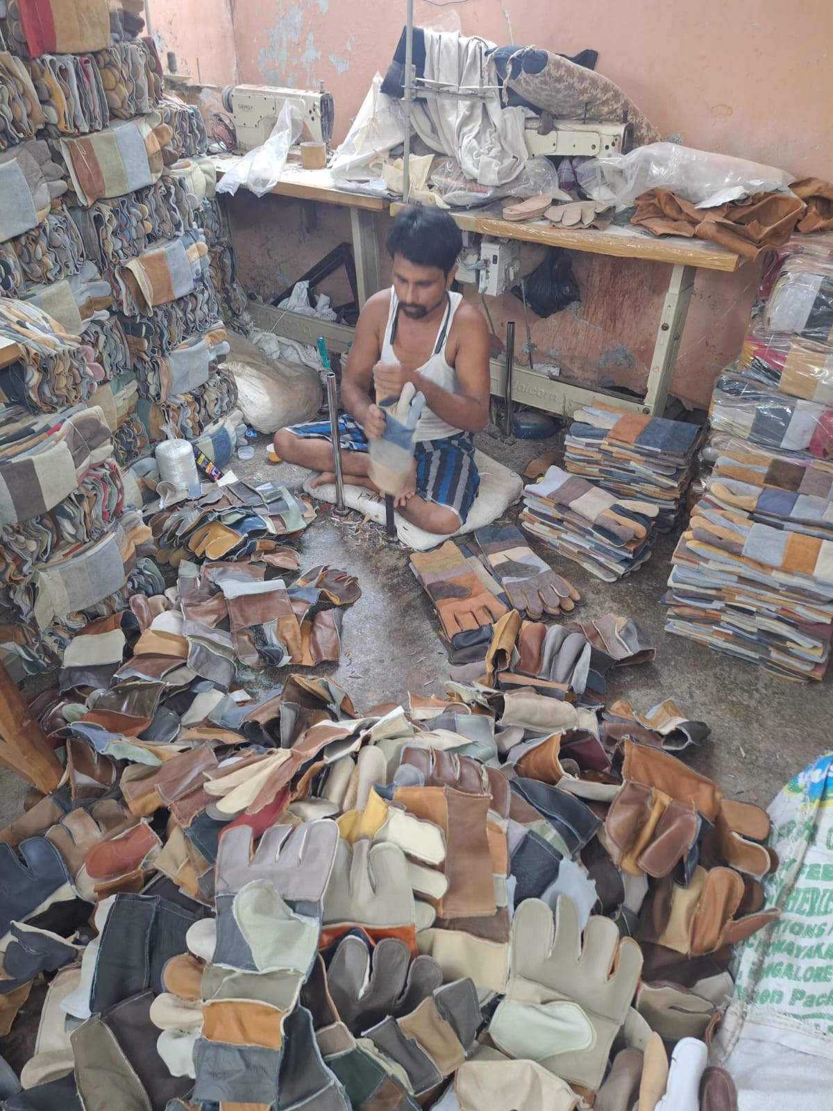 Worker assembling stacks of finished leather gloves