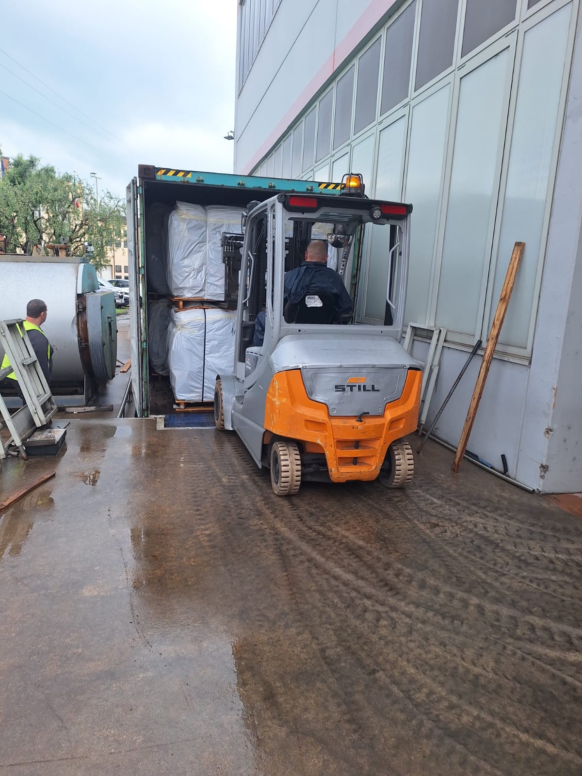 Forklift loading palletised leather bales into shipping container in Europe